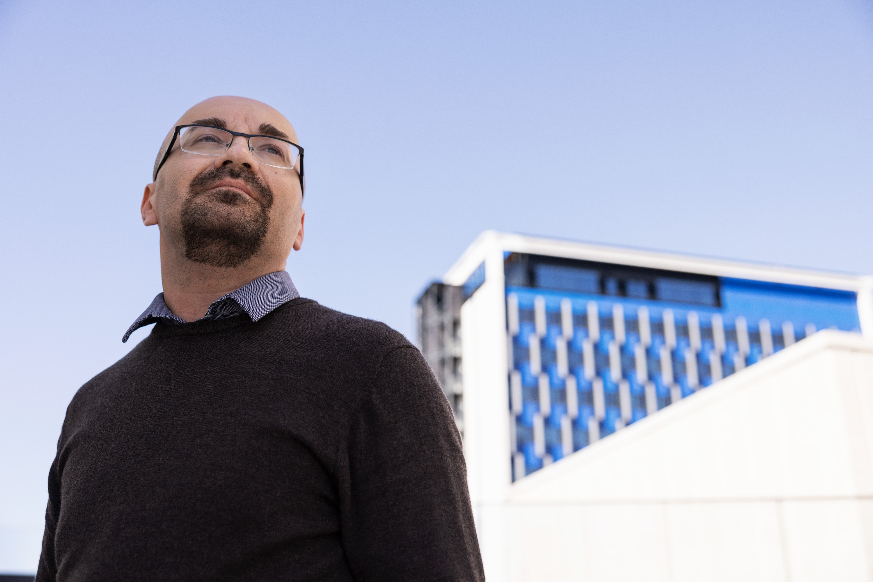 Mann som ser utover, bygning i bakgrunnen