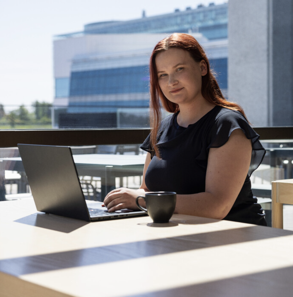 Kvinne foran laptop stirrer mot kamera