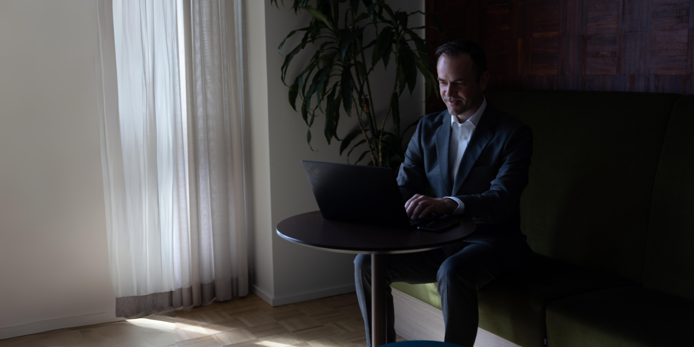 Mann med laptop sitter ved et bord og jobber