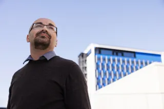 Mann som ser utover, bygning i bakgrunnen