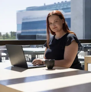 Kvinne foran laptop stirrer mot kamera
