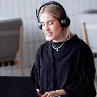 Kvinne som sitter med bena i kryss med pc og headset